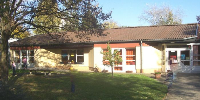 Exterior view of a Montessori kindergarten building in Düsseldorf with playground area and green lawn