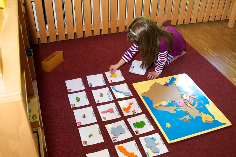 Child in a classroom working with a geography puzzle map and country cards for hands-on learning