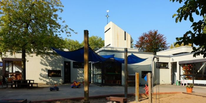 Montessori kindergarten Düsseldorf exterior with playground, shade sails, and modern building design