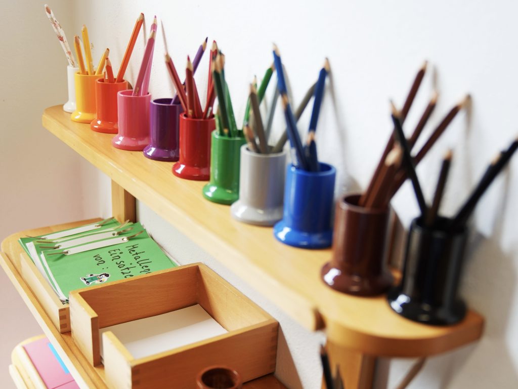 organized colored pencil holders and writing materials for creative learning in a kindergarten