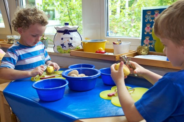 Children in a Montessori kindergarten peeling potatoes as part of practical life activities for hands-on learning
