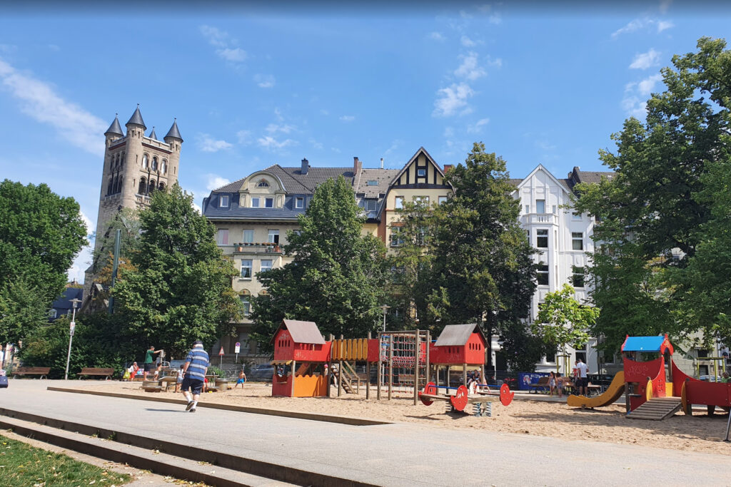 Fürstenplatz - Outdoor playground in Düsseldorf with climbing structures, slides, and historic buildings in the background