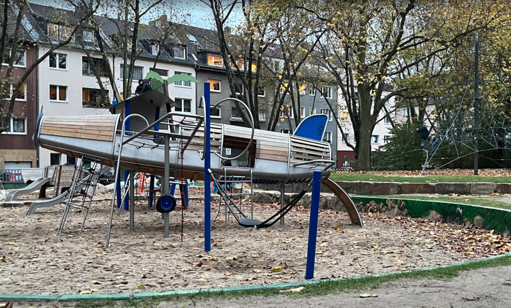 Playground Hermannsplatz – Airplane-themed climbing structure at an outdoor playground in Düsseldorf surrounded by autumn trees"