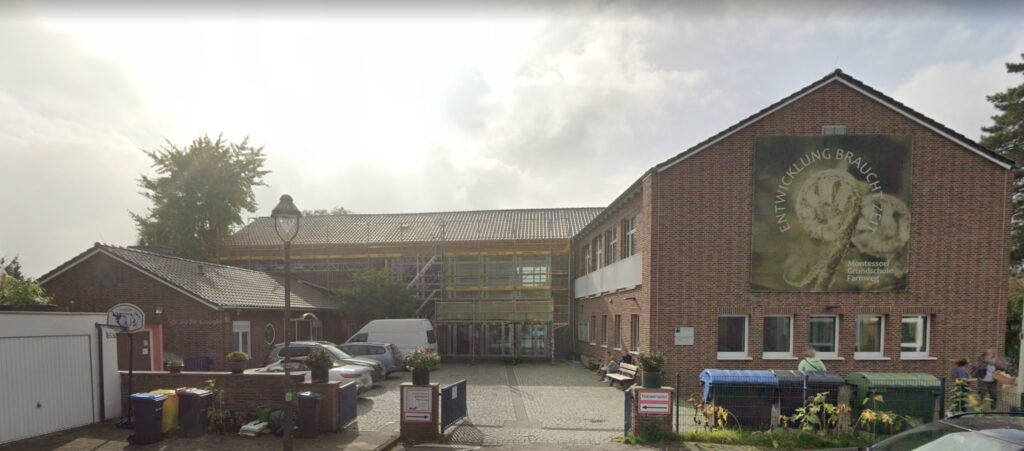 Montessori Grundschule Farnweg front view with educational banners on brick wall
