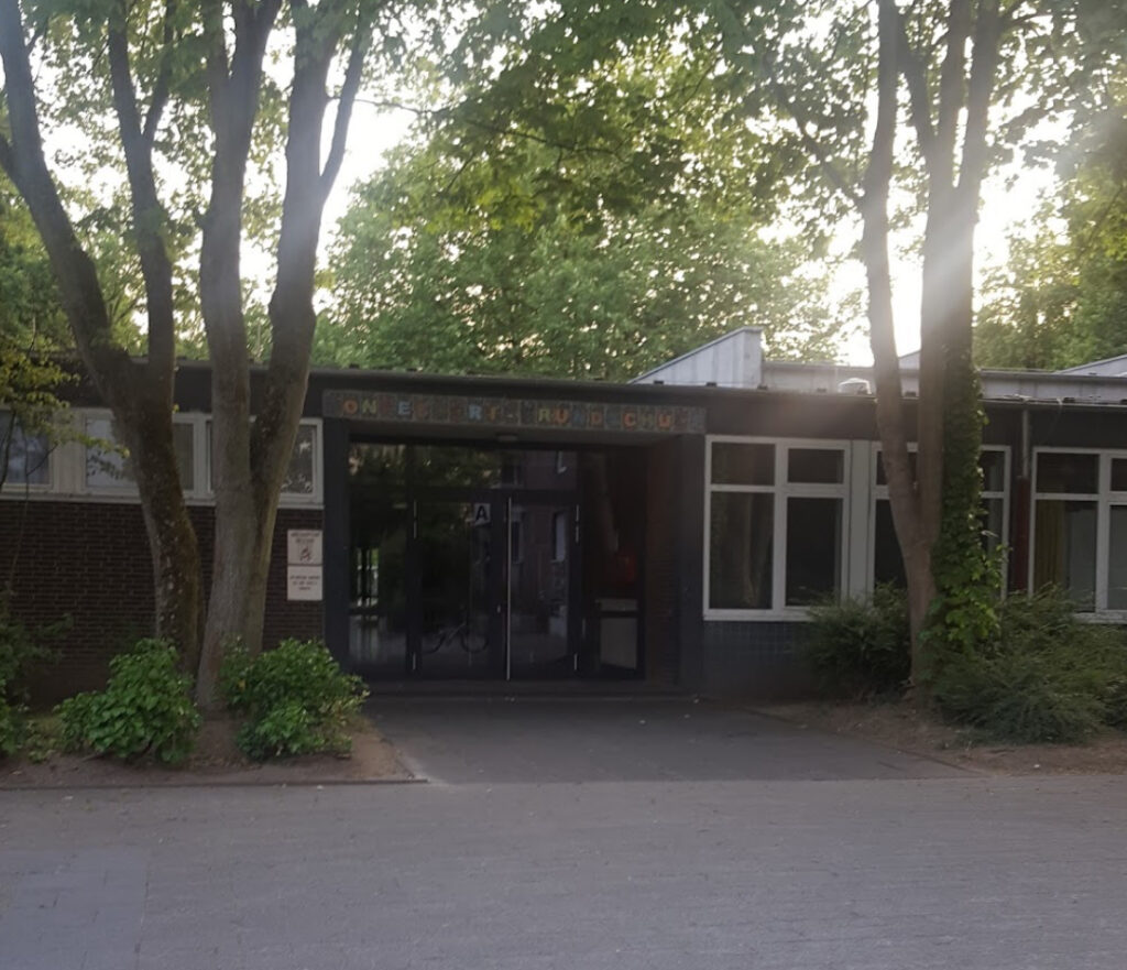 Tree-lined courtyard of Montessori Grundschule Düsseldorf Süd during spring
