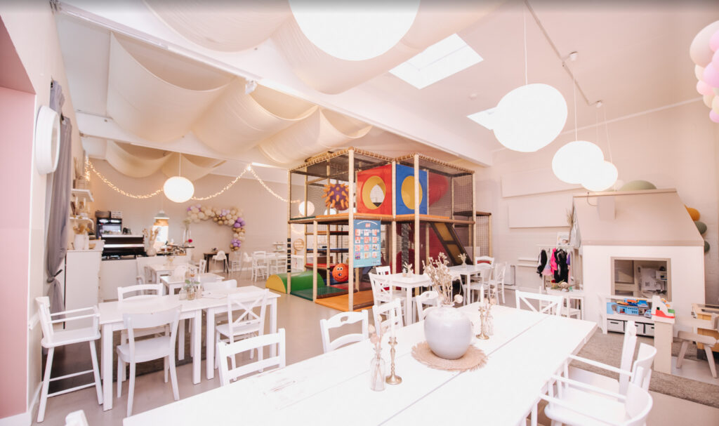 Bright and welcoming café with indoor play area, climbing structure, and child-sized furniture