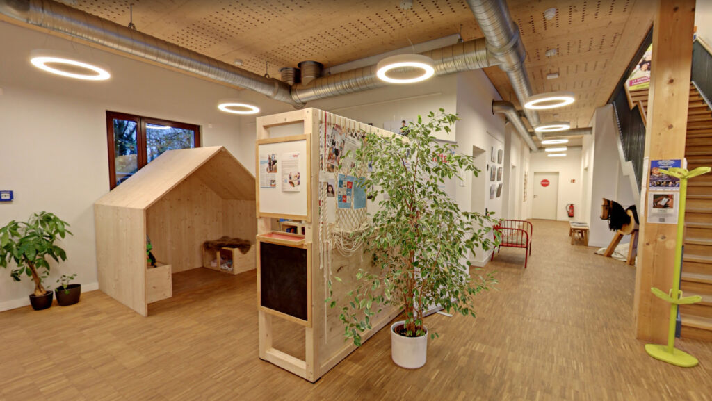 Modern indoor learning and play space for children with wooden playhouse, interactive wall, and natural design elements