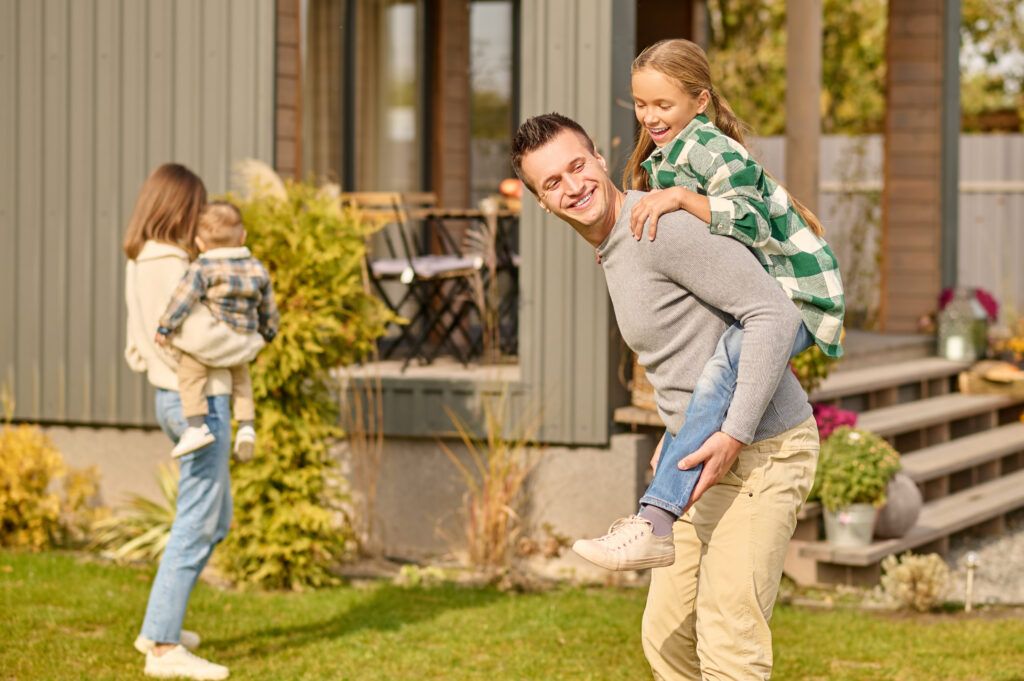 Smiling parents with children playing in front of modern family home

