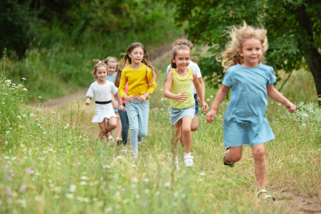 Group of children running through a meadow on a sunny day

