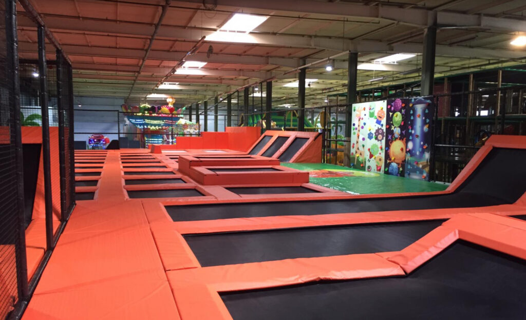 Large indoor trampoline area in NRW with angled walls and colorful climbing structures in a kids activity center