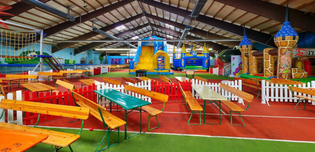 Indoor playground in NRW with inflatable castles, large slides, and family seating area for children's birthday parties and playtime