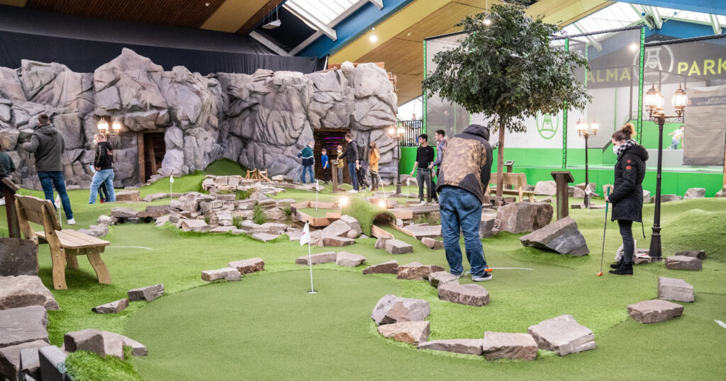 Themed mini golf with artificial turf, rock formations, and immersive cave-style decor