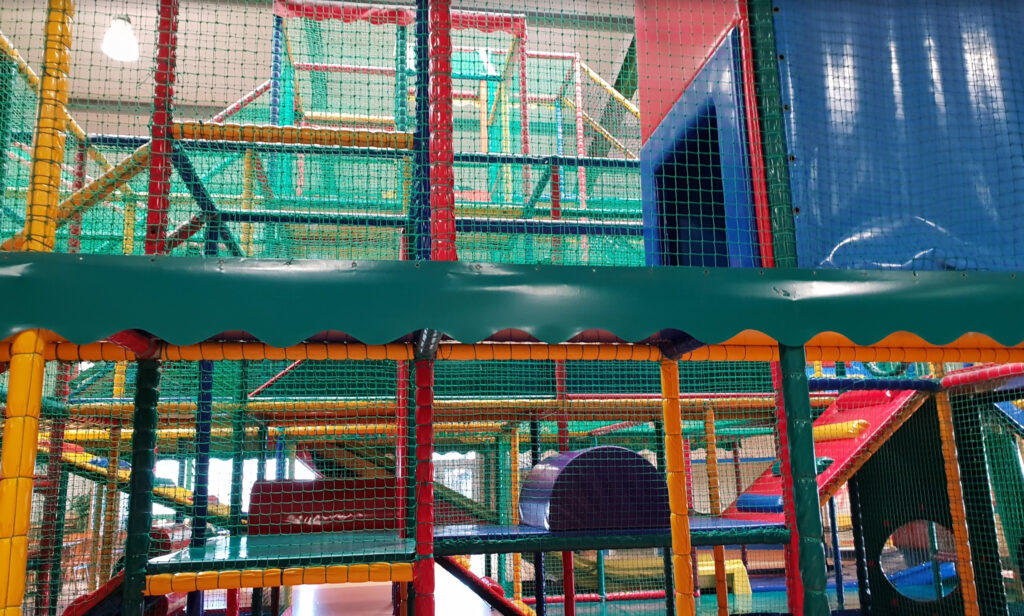 Indoor playground in NRW with multi-level climbing maze, tunnels, and colorful padded play structures for children