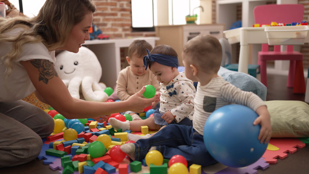 Babies and a caregiver playing with colorful toys in a daycare environment

