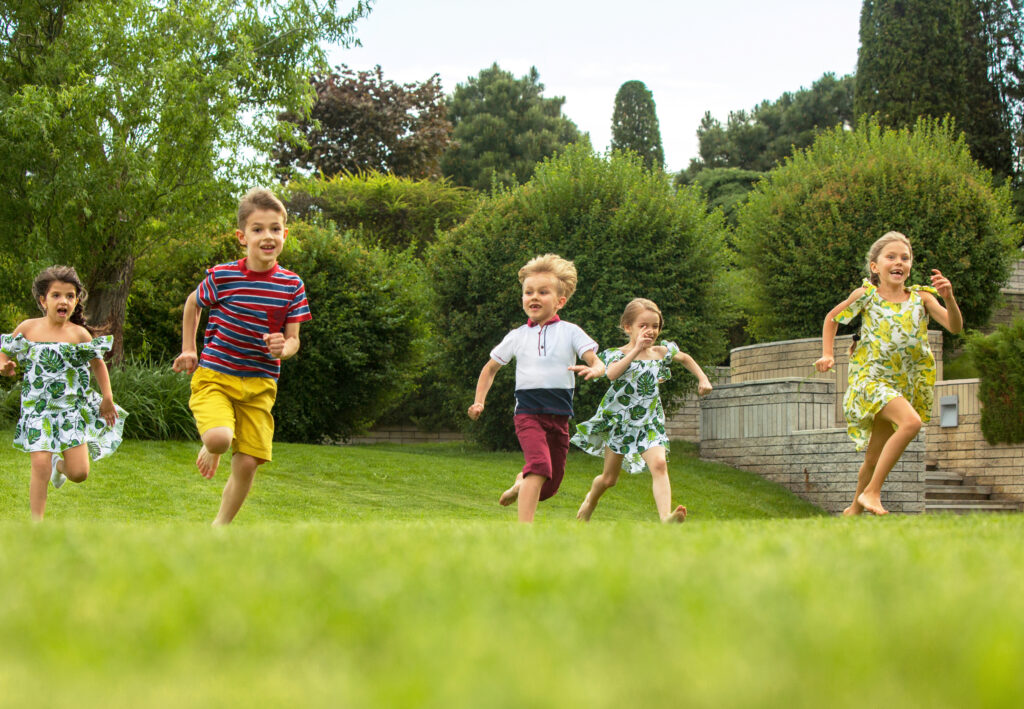 Group of happy children running and playing in a green park