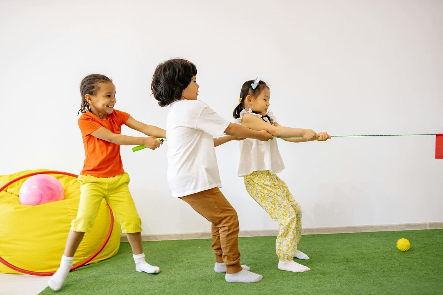 Children playing tug-of-war during a gymnastics class for kids in Düsseldorf, developing teamwork and motor skills through fun indoor activities