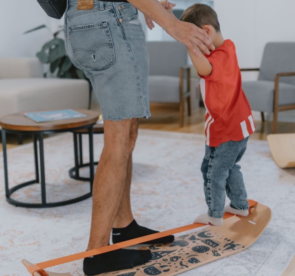 Parent and toddler practicing phisical activities together on balance equipment in a home environment