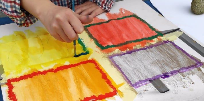 engaging in hands-on creative work, absorbing knowledge through sensory experience — painting, reflecting the absorbent mind principle.

