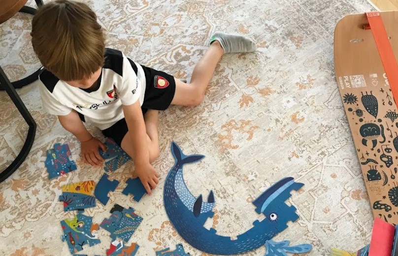 Illustrative image for the Toys vs touchscreens guide: Young child building a puzzle on the floor, illustrating hands-on learning as an alternative to screen time.

