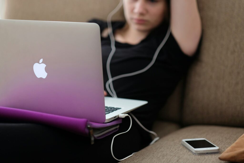 Teenager using a laptop with headphones — highlighting the importance of screen-time balance when introducing coding for children the Montessori way.

