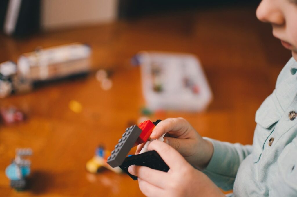 Young child building with LEGO bricks — showcasing hands-on learning and real-world logic development in Montessori coding activities.

