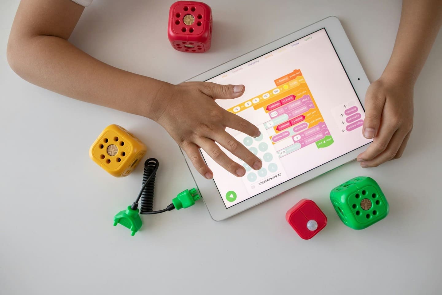 Child programming with Montessori-friendly AI blocks and an educational tablet app, demonstrating early digital literacy in a Montessori setting
