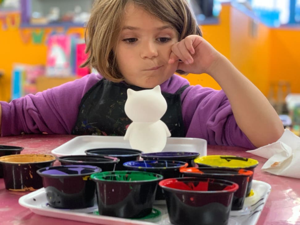 Illustrative image for the "Is Montessori right for my child" guide: Girl painting in a colorful classroom — reflecting child-led exploration and decision-making in a Montessori learning environment.