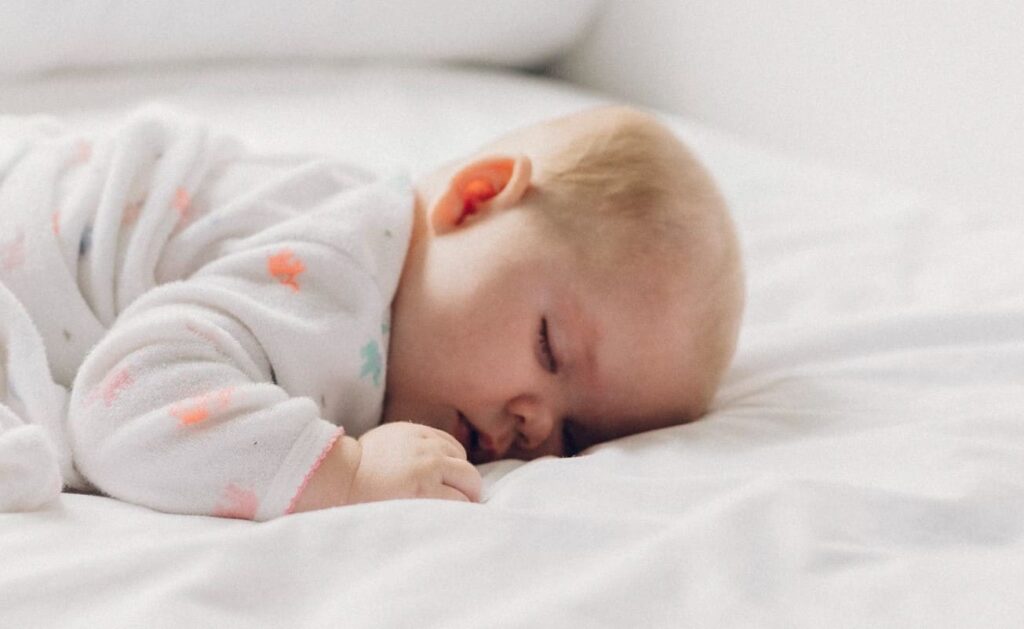 Infant sleeping on a low mattress, showcasing a minimalist baby-friendly sleep setup aligned with the Montessori approach to sleep
