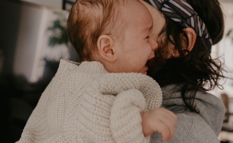 Father comforting a crying baby, highlighting common concerns parents face when transitioning to a Montessori sleep environment