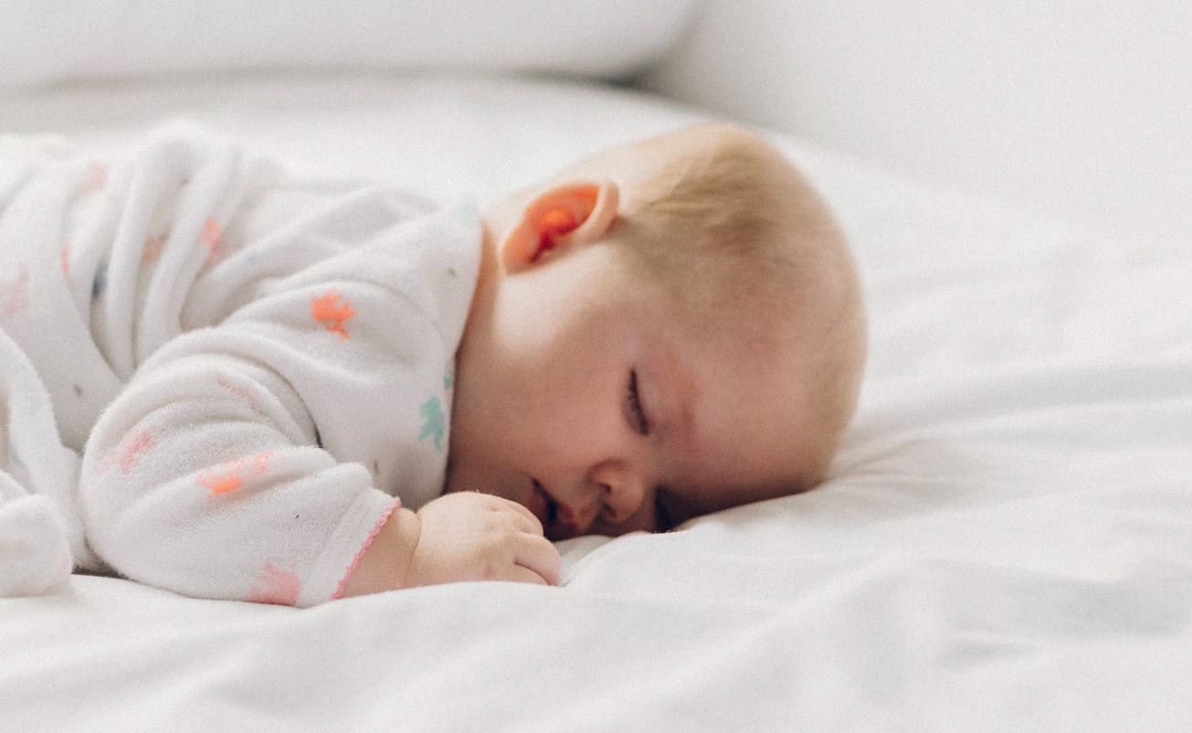 Infant sleeping on a low mattress, showcasing a minimalist baby-friendly sleep setup aligned with the Montessori approach to sleep