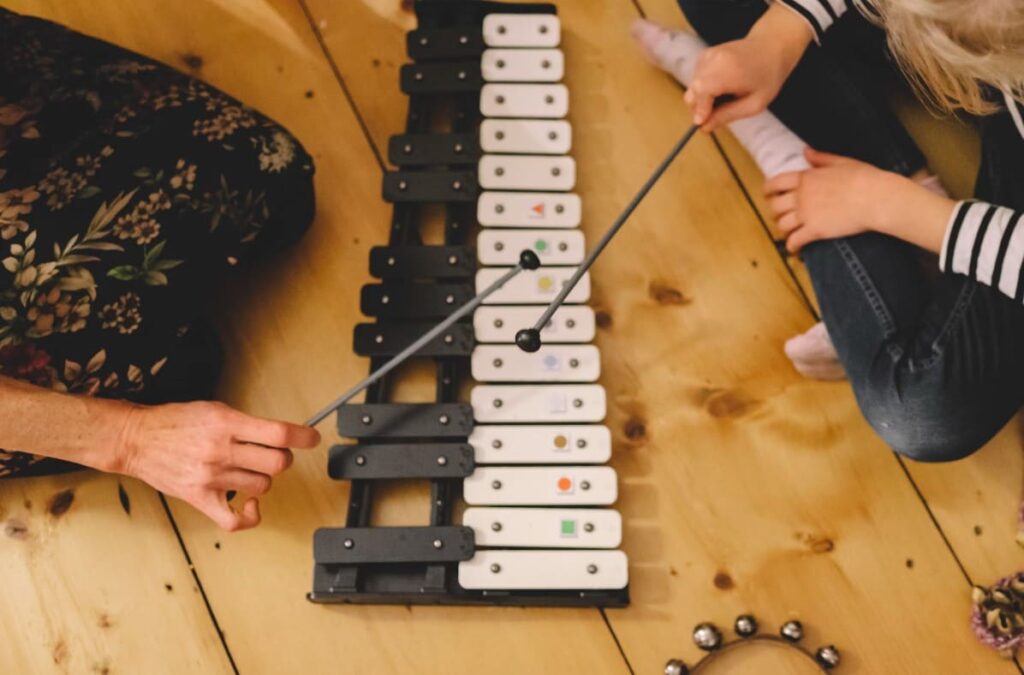 Montessori music curriculum in action – child learning rhythm and melody with xylophone through hands-on Montessori activities.