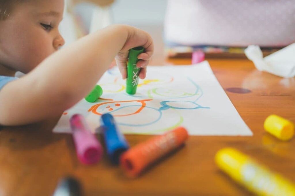 Child drawing with colorful markers in a Montessori-inspired learning space — illustrating how Montessori supports ADHD through creativity and independence.

