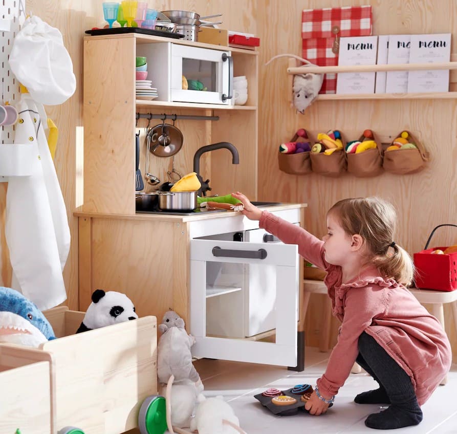 Toddler interacting with a modified IKEA Duktig kitchen, showcasing a creative DIY Montessori play kitchen adapted for functional learning.

