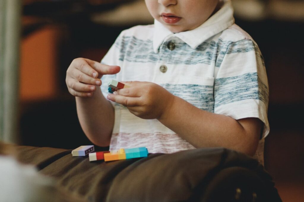 A child focusing on connecting building blocks — highlighting hands-on activities in a Montessori classroom, addressing the question: is Montessori good for autism?