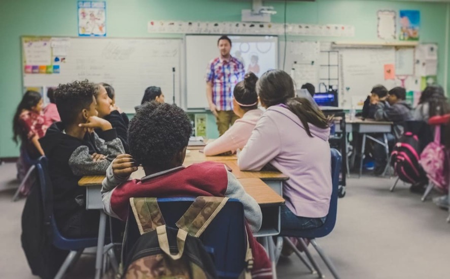 Children in a diverse classroom attentively listening to a teacher — a snapshot of modern education in Germany