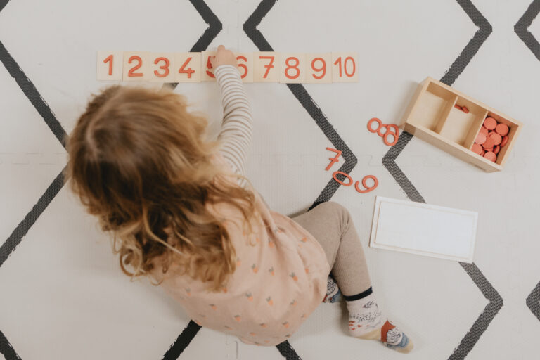 Child working with Montessori materials on a mat in a calm, open environment