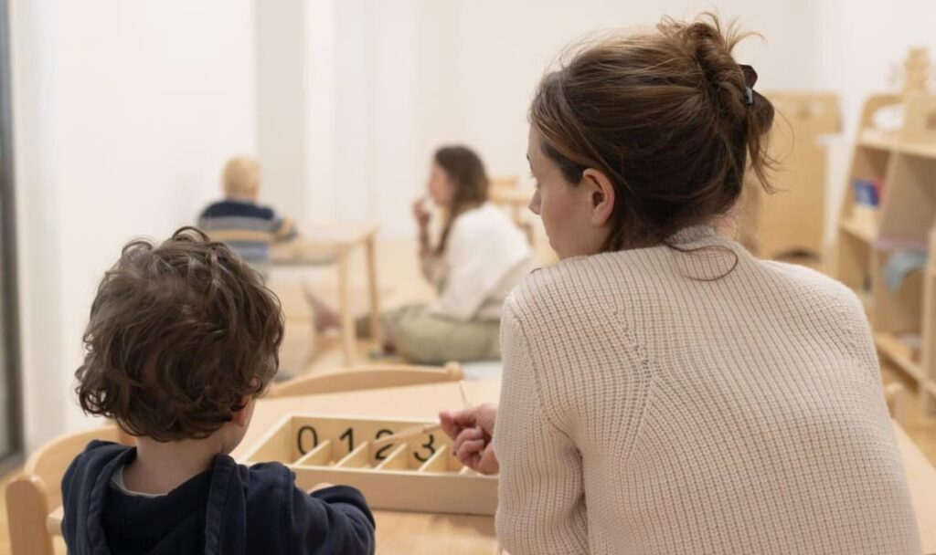 Montessori guide working with a child using wooden number tiles — showcasing alternative learning within Germany’s educational framework.