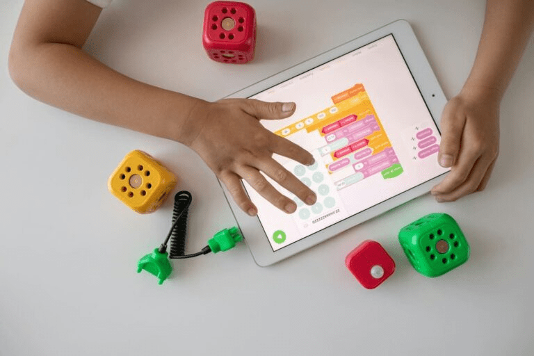 Child programming with Montessori-friendly AI blocks and an educational tablet app, demonstrating early digital literacy in a Montessori setting