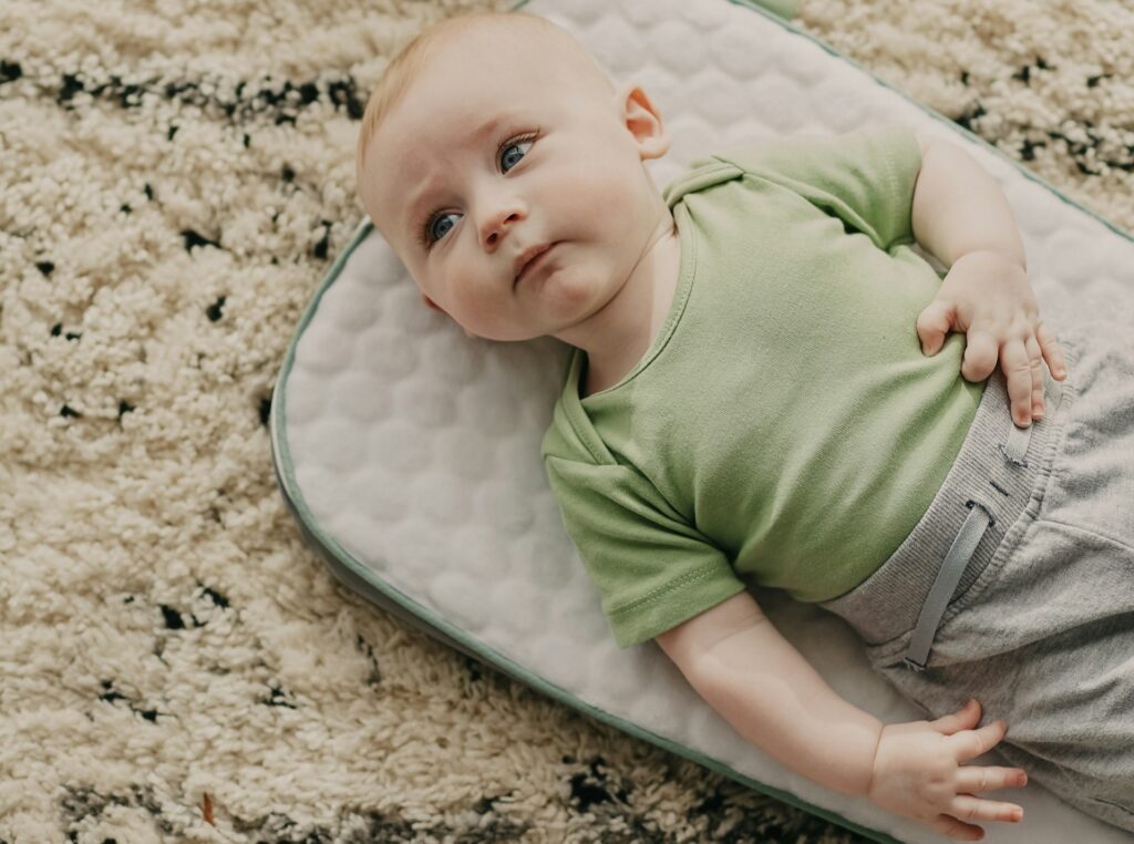 Baby relaxing on a soft mat before beginning tummy time or early mobility practice.