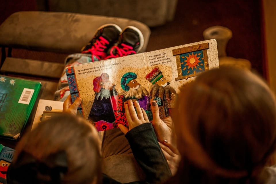A child reading a culturally diverse picture book in a bilingual setting, supporting early literacy, language comprehension, and meaningful learning through storytelling.